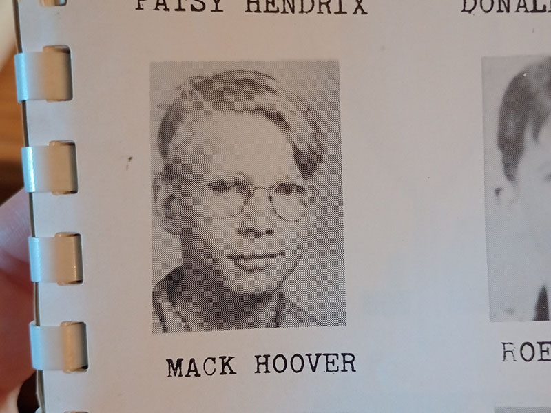 A black and white yearbook portrait photo of Mack Hoover from a spiral bound yearbook.  Mack appears to be in his early teens or perhaps slightly younger, with light straight hair parted to the viewer'd right, glasses, and a small smile.  He is looking into the camera.